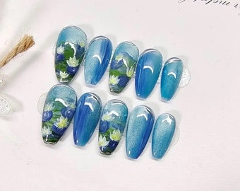 May include: Set of ten blue and white false nails with a floral design. The nails are long and oval shaped.