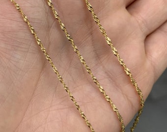 May include: Three gold rope chains of varying lengths, displayed on a hand.