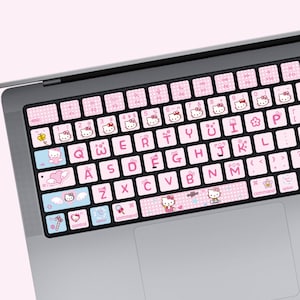 May include: Pink and white Hello Kitty keyboard stickers with a polka dot pattern. The stickers feature Hello Kitty characters and symbols. The stickers are designed for a standard laptop keyboard.