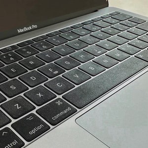 May include: A silver MacBook Pro laptop with a black keyboard and a trackpad. The keyboard has the letters 'MacBook Pro' printed on the top row.