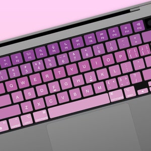 May include: A close-up of a laptop keyboard with a gradient pink and purple color scheme. The keys are labeled with the standard letters, numbers, and symbols. The keyboard has a silver finish and a trackpad.