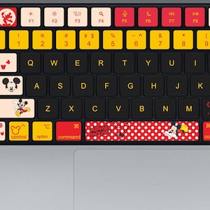 May include: A black keyboard with yellow, red, and white keys. The keyboard has a Mickey Mouse theme, with images of Mickey and Minnie Mouse on some keys. The keyboard also has function keys and number keys.