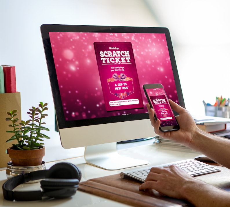 Peut inclure: Un &eacute;cran d'ordinateur affichant un ticket &agrave; gratter d'anniversaire rose et blanc avec le texte "Birthday Scratch Ticket" et "A Trip to New York". Une personne tient un smartphone avec un ticket &agrave; gratter similaire &agrave; l'&eacute;cran.