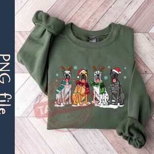 May include: Green sweatshirt with a Christmas-themed design featuring four Great Danes wearing Santa hats and scarves. The dogs are decorated with lights and snowflakes.