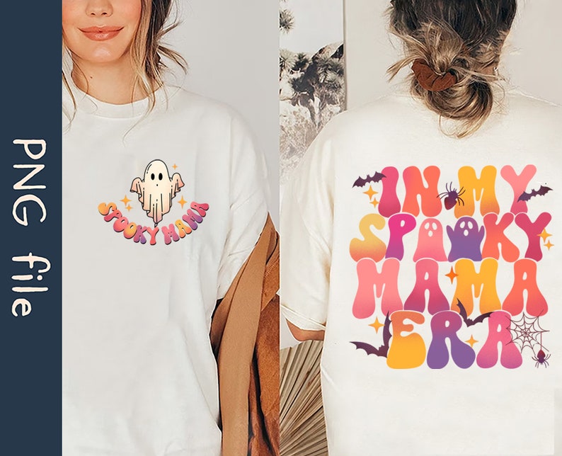 Op de afbeelding: Twee witte T-shirts met een Halloween-thema. De voorkant van het ene shirt heeft een spook met de tekst "Spooky Mama" in regenboogkleuren. De achterkant van het andere shirt heeft de tekst "In My Spooky Mama Era" in regenboogkleuren met een spin, een spinnenweb en vleermuizen.