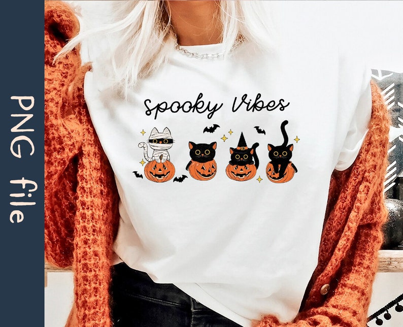 May include: White t-shirt with the text "Spooky Vibes" and a graphic of four black cats dressed in Halloween costumes sitting on pumpkins.