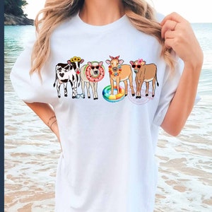 May include: White t-shirt with a graphic of four cows wearing sunglasses and floral headbands. The cows are standing in a line and the one in the middle is holding a rainbow float.