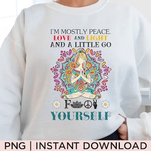 Op de afbeelding: Witte trui met een kleurrijk mandala-ontwerp en de tekst "I'm mostly peace. Love and light and a little go f yourself."
