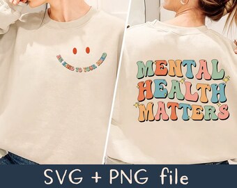 May include: Two beige sweatshirts with colorful text. The first sweatshirt has a smiley face with the text "Be Kind to Your Mind". The second sweatshirt has the text "Mental Health Matters".