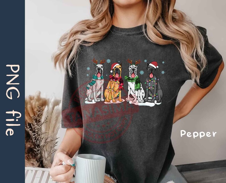 May include: A dark gray t-shirt with a graphic of four Great Danes wearing Santa hats and reindeer antlers. The dogs are wearing festive scarves and have Christmas lights around them. The text "Pepper" is visible in the bottom right corner of the image.