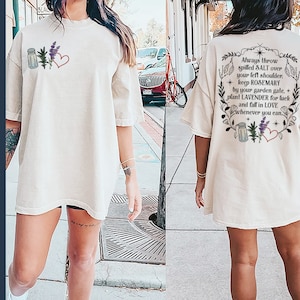 May include: A white oversized t-shirt with a graphic design on the back that says "Always throw spilled SALT over your left shoulder. Keep ROSEMARY by your garden gate. Plant LAVENDER for luck and fall in LOVE whenever you can."