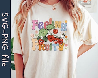 May include: A white t-shirt with a colorful graphic design featuring the text "Feeling Fruity" with strawberries and flowers.