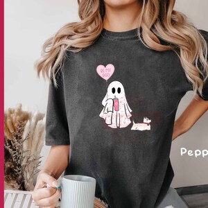 Puede incluir: Una camiseta gris con un fantasma sosteniendo un globo de coraz&oacute;n rosa que dice "Be My Boo" y un perro peque&ntilde;o con corazones rosas en &eacute;l. El texto "Pepper" est&aacute; en la esquina inferior derecha de la camiseta.