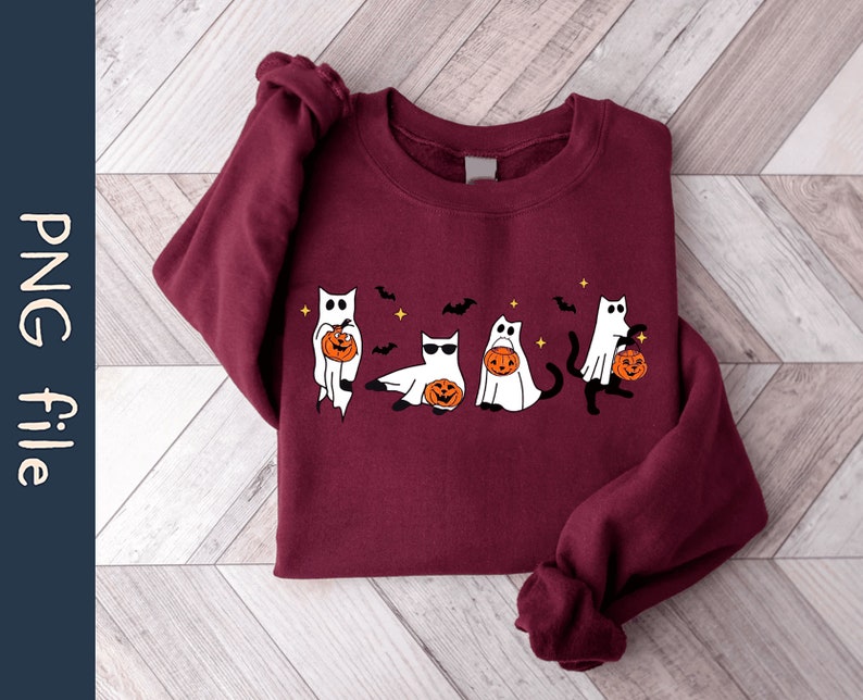 May include: A maroon sweatshirt featuring a Halloween-themed design. The graphic depicts five cartoon cats dressed as ghosts, each holding a jack-o'-lantern. Bats and stars are also included in the design. The words "PNG file" are on the left side of the image.