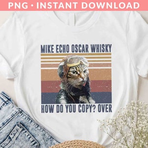 May include: White t-shirt with a vintage-style graphic of a cat wearing aviator goggles. The text reads "Mike Echo Oscar Whisky How Do You Copy? Over".