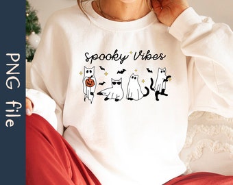 Puede incluir: Sudadera blanca con el texto "Spooky Vibes" impreso en la parte delantera. El diseño presenta cuatro gatos de dibujos animados vestidos de fantasmas, uno de ellos sosteniendo una calabaza.