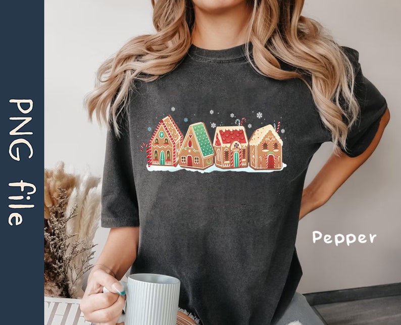 May include: A black t-shirt with a graphic of gingerbread houses decorated with candy and frosting. The text "Pepper" is printed on the bottom right corner of the shirt.