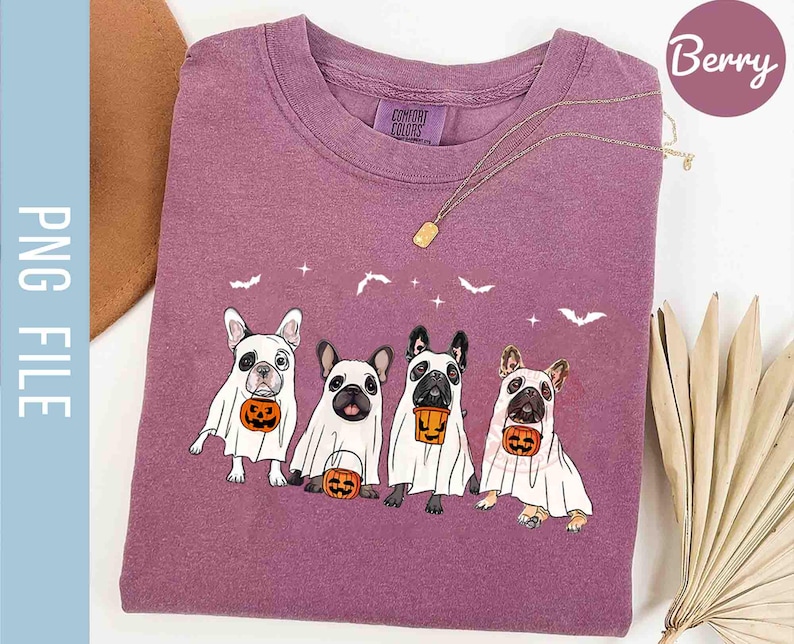 Pu&ograve; includere: Una maglietta viola con una grafica di quattro bulldog francesi vestiti da fantasmi per Halloween. Ogni cane tiene una piccola zucca. Il testo "Comfort Colors" &egrave; visibile sulla maglietta.