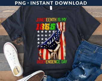 May include: A black t-shirt with a graphic design of an American flag being held by a hand. The flag is torn and the text "Juneteenth is my 1865 Independence Day" is printed on the shirt.