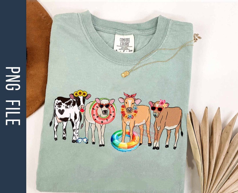 May include: A light green t-shirt with a graphic of four cows wearing sunglasses, flower crowns, and holding pool floats. The text "Comfort Colors" is visible on the shirt.