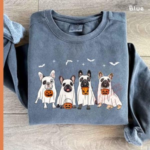 Pu&ograve; includere: Una felpa blu jeans con una grafica di quattro bulldog francesi vestiti da fantasmi che tengono secchi di Halloween. Il testo "Blue Jean" &egrave; nell'angolo in alto a destra dell'immagine.
