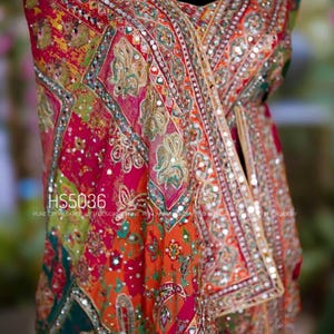 May include: A vibrant, ornate textile with intricate embroidery and mirror work. The fabric features a patchwork design in shades of red, orange, green, and yellow. The text "HS5036" is visible.