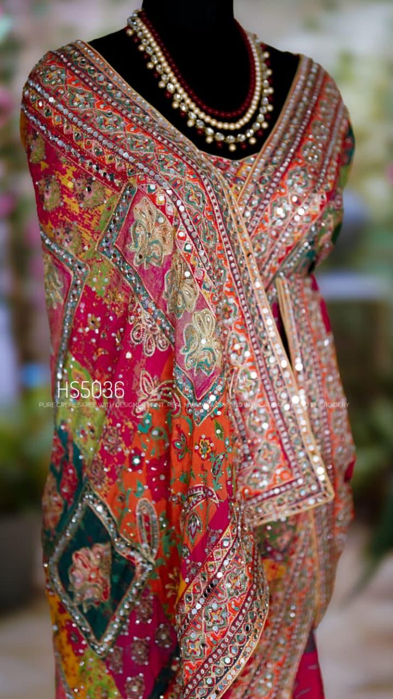 May include: A vibrant, ornate textile with intricate embroidery and mirror work. The fabric features a patchwork design in shades of red, orange, green, and yellow. The text "HS5036" is visible.