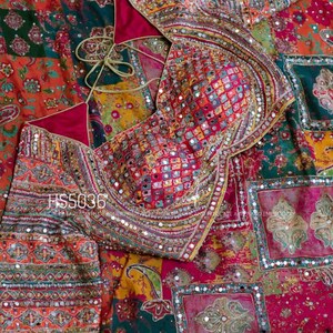 May include: A vibrant, patchwork-style textile featuring a blouse and fabric with intricate embroidery and mirror embellishments. The blouse has a deep pink lining and a tie closure. The fabric displays a variety of colors and patterns, including paisley and floral designs. The text "HS5036" is visible.