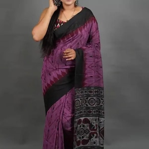 Può includere: Un sari di cotone viola e nero con un motivo geometrico e un bordo nero. Il sari ha un bordo bianco e nero con un motivo paisley.