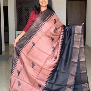 May include: A pink and black silk saree with a black border and a gold trim. The saree has a pattern of small black owls on the pink fabric.