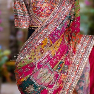 May include: A colourful saree with detailed embroidery and mirror embellishments. The saree has a patchwork design in pink, green, yellow, and orange. The blouse has a square neckline and short sleeves, also decorated with embellishments. The text "HS5036" is visible.
