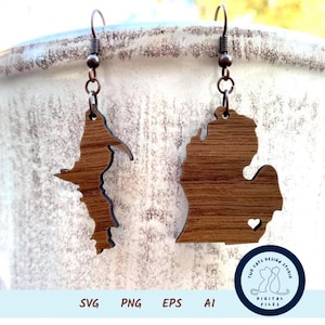 Puede incluir: Un par de pendientes de madera con forma del estado de Michigan. Los pendientes son marrones y tienen un corazón recortado en la península inferior. Los pendientes cuelgan de ganchos de cobre. La imagen también incluye un logotipo para "Two Cats Design Studio" con el texto "Archivos digitales".