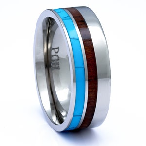 May include: A silver titanium ring with a turquoise and wood inlay. The ring is engraved with the letters "POHI".