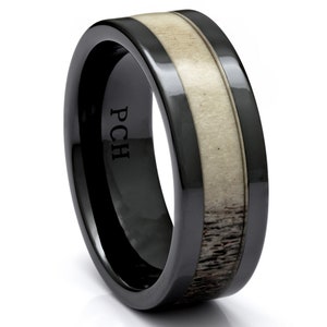 May include: Black ceramic ring with a band of white and brown stag antler. The ring is engraved with the initials "PCH".