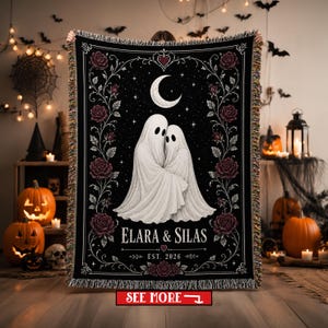 May include: A black woven throw blanket featuring two white ghosts embracing under a crescent moon and stars. The design includes dark red roses along the sides and bottom, with the text ELARA & SILAS and EST. 2026 printed in white lettering.