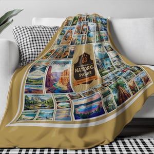 May include: A tan throw blanket with a collage of vintage postcard images of 63 National Parks. The blanket features a large, gold circle with the text "63 National Parks" and "Wilderness & Wonder".
