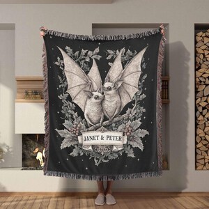 May include: Black and white throw blanket with a design of two bats with the text "Janet & Peter" in a decorative banner.