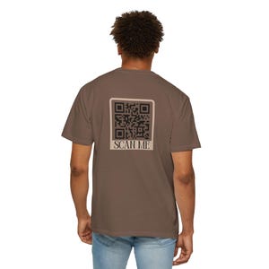 May include: A brown t-shirt with a black and white QR code and the text "SCAN ME" printed on the back.