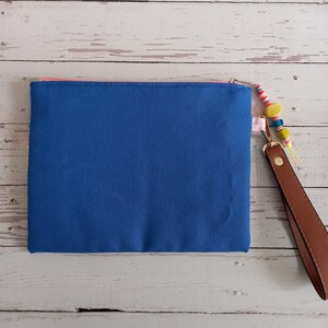 May include: A blue canvas zippered pouch with a pink zipper and a brown leather strap with colourful beads.
