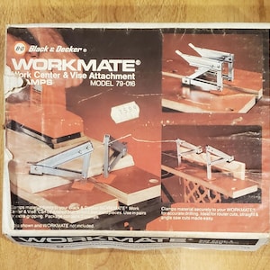May include: A Black & Decker Workmate Work Center & Vise Attachment box, model 79-016. The packaging features images of metal clamps secured to a wooden workbench, demonstrating their use for holding materials firmly in place.