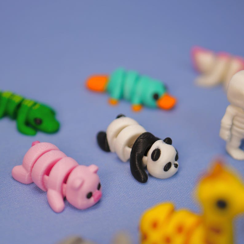 Op de afbeelding: Een verzameling kleine, kleurrijke, 3D-geprinte dierenfiguren. De figuren zijn gemaakt van plastic en zijn ontworpen om te worden gearticuleerd. De dieren omvatten een panda, een varken, een vogelbekdier, een krokodil en een giraffe.