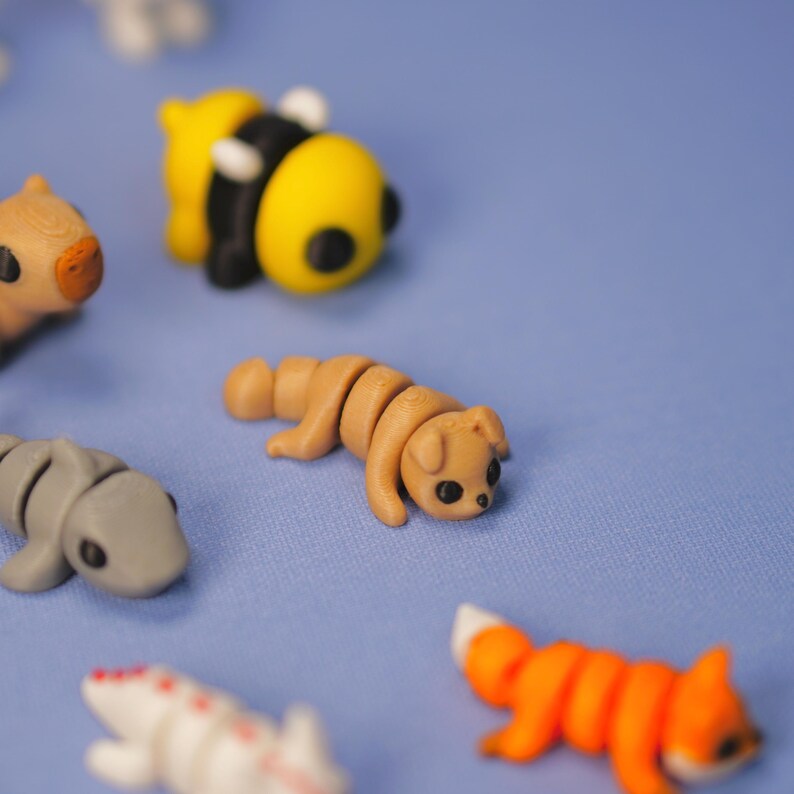 Op de afbeelding: Een verzameling kleine, kleurrijke dierenfiguren gemaakt van polymer clay. De figuren omvatten een ​​bij, een hond, een vos, een haai en een capibara.