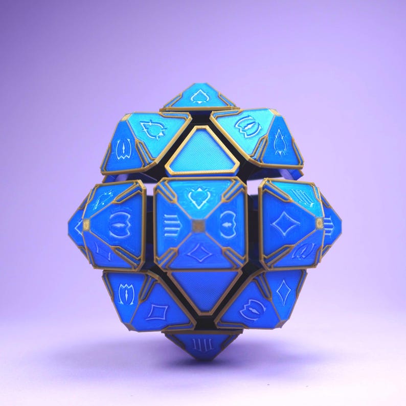 May include: A blue and gold geometric dice with various symbols on each face. The dice is made of a hard plastic material and has a shiny finish.