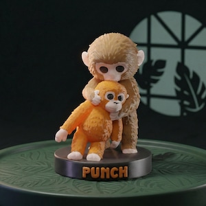 May include: A charming figurine of two monkey figures. A larger, brown monkey embraces a smaller, orange monkey. The base is dark grey with the word "PUNCH" in orange letters. The monkeys have white accents on their hands and feet.