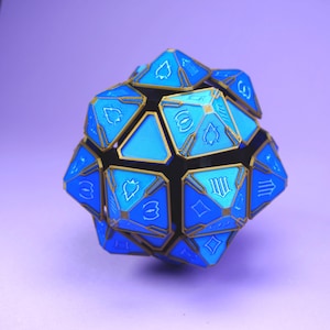 May include: A blue and gold geometric dice with various symbols on each face. The dice is made of plastic and has a shiny finish.