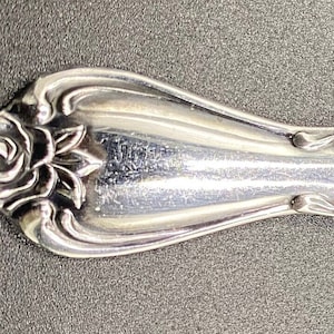 Peut inclure: Une fourchette en argent avec un motif de rose décoratif sur le manche.