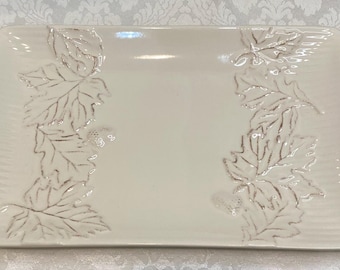 May include: A white rectangular serving platter with a raised design of silver leaves around the border.