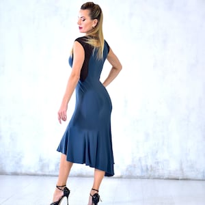 May include: A woman wearing a blue dress with a black mesh panel in the back. The dress has a flared skirt and is knee-length. She is wearing black heels.