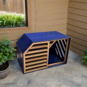May include: A blue wooden dog house with a slatted wooden door and a blue interior. The house is sitting on a grey concrete patio.