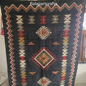 May include: Black and white rug with geometric patterns in red, orange, and yellow. The rug has a fringe border and the text "Balajjiartcrafts" is printed in the top center.